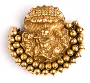 A gold braid ornament depicting Lord Krishna playing his flute under the hooded Naga
